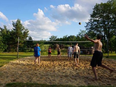 Jugendliche spielen gemeinsam Volleyball im Ferienlager für Jugendliche im Sommer.